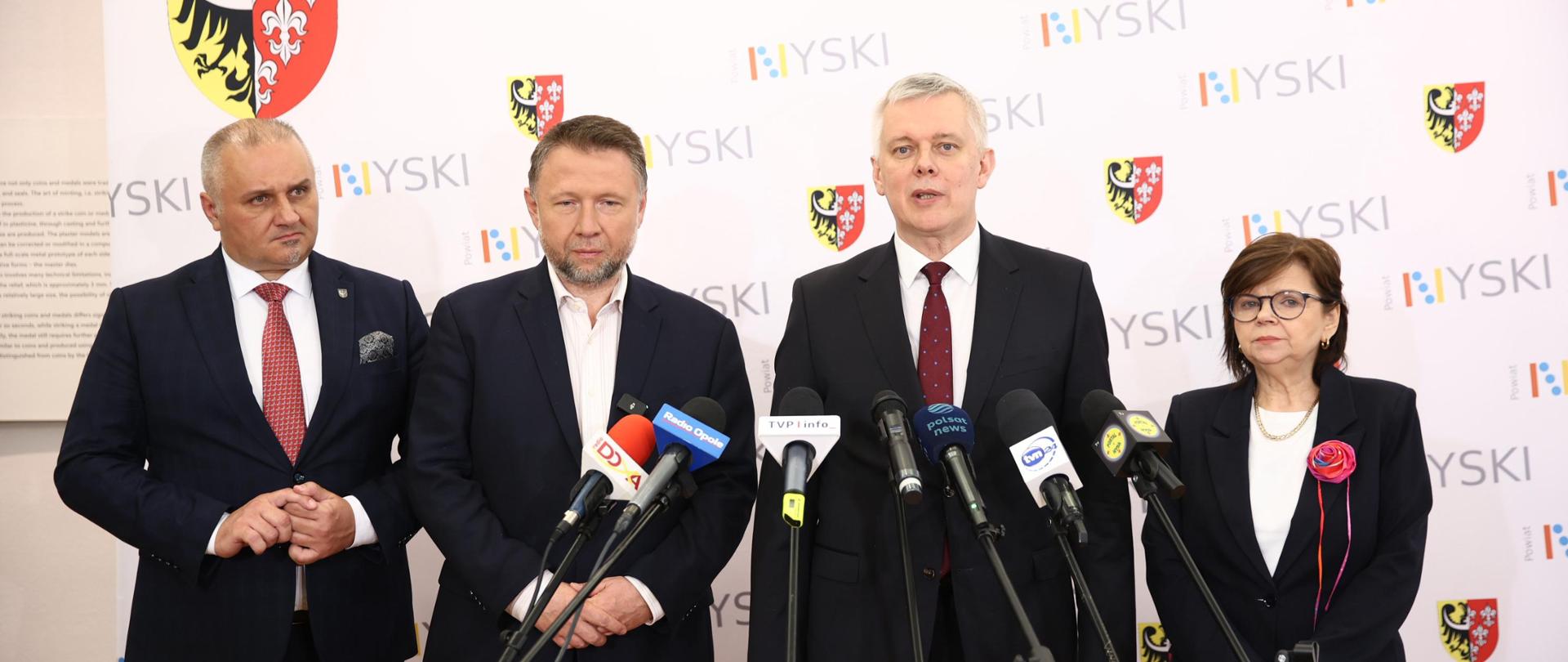 Szef #MSWiA @TomaszSiemoniak podczas briefingu prasowego wraz z ministrą edukacji Izabelą Leszczyną - po prawej, ministrem Marcinem Kierwińskim i starostą nyskim Danielem Palimąką - po lewej stronie. Przed ministrem stoją mikrofony. W tle biała ścianka z napisem Nyski.
