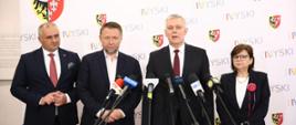 Szef #MSWiA @TomaszSiemoniak podczas briefingu prasowego wraz z ministrą edukacji Izabelą Leszczyną - po prawej, ministrem Marcinem Kierwińskim i starostą nyskim Danielem Palimąką - po lewej stronie. Przed ministrem stoją mikrofony. W tle biała ścianka z napisem Nyski.