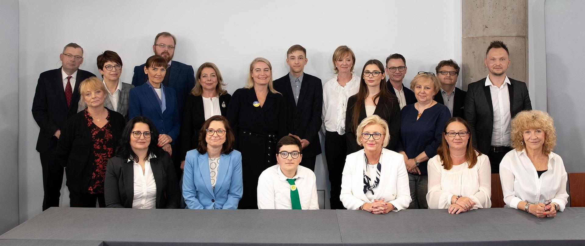 Zdjęcie zbiorowe uczestników debaty, stoją na tle białej ściany.