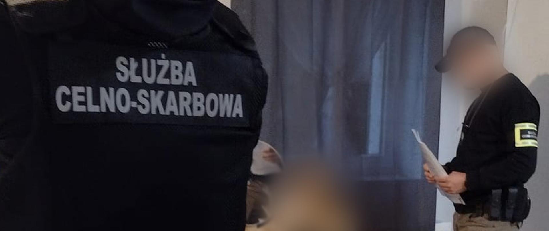 Funkcjonariusze Służby Celno-Skarbowej prowadzą czynności w pomieszczeniu.