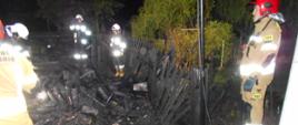 Zdjęcie przedstawia strażaków i spalone zgliszcza 