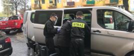 Zdjęcie przedstawia strażaków udzielających pomocy podczas wsiadania do samochodu osobie starszej celem dowozu do punktu szczepień.