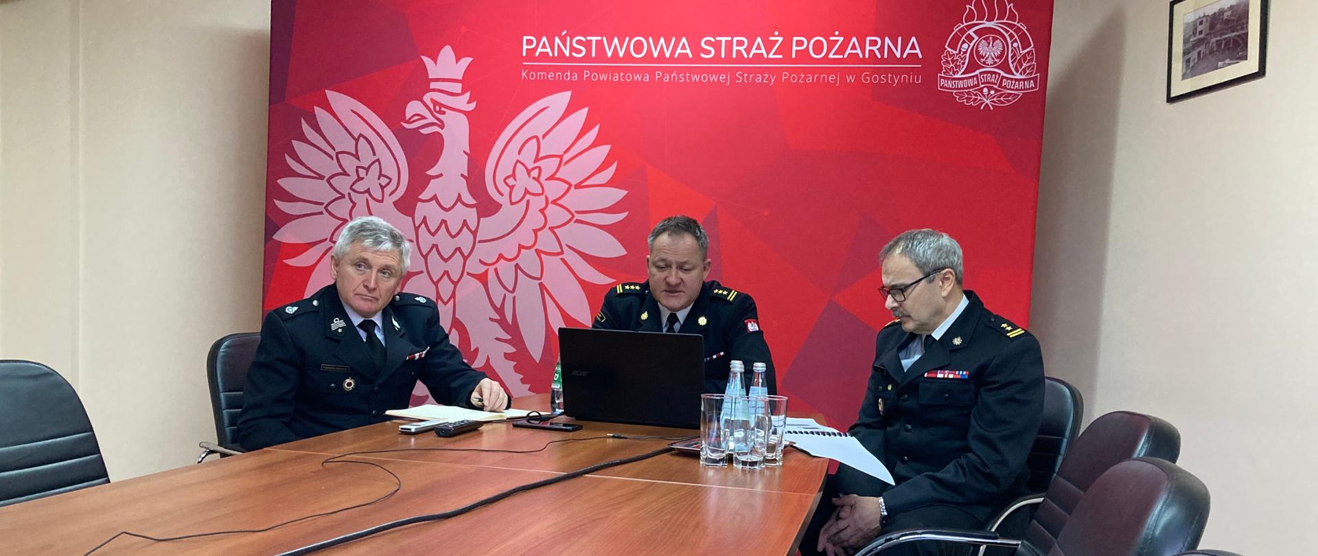 Zdjęcie przedstawia funkcjonariuszy siedzących przy stole w sali konferencyjnej. 