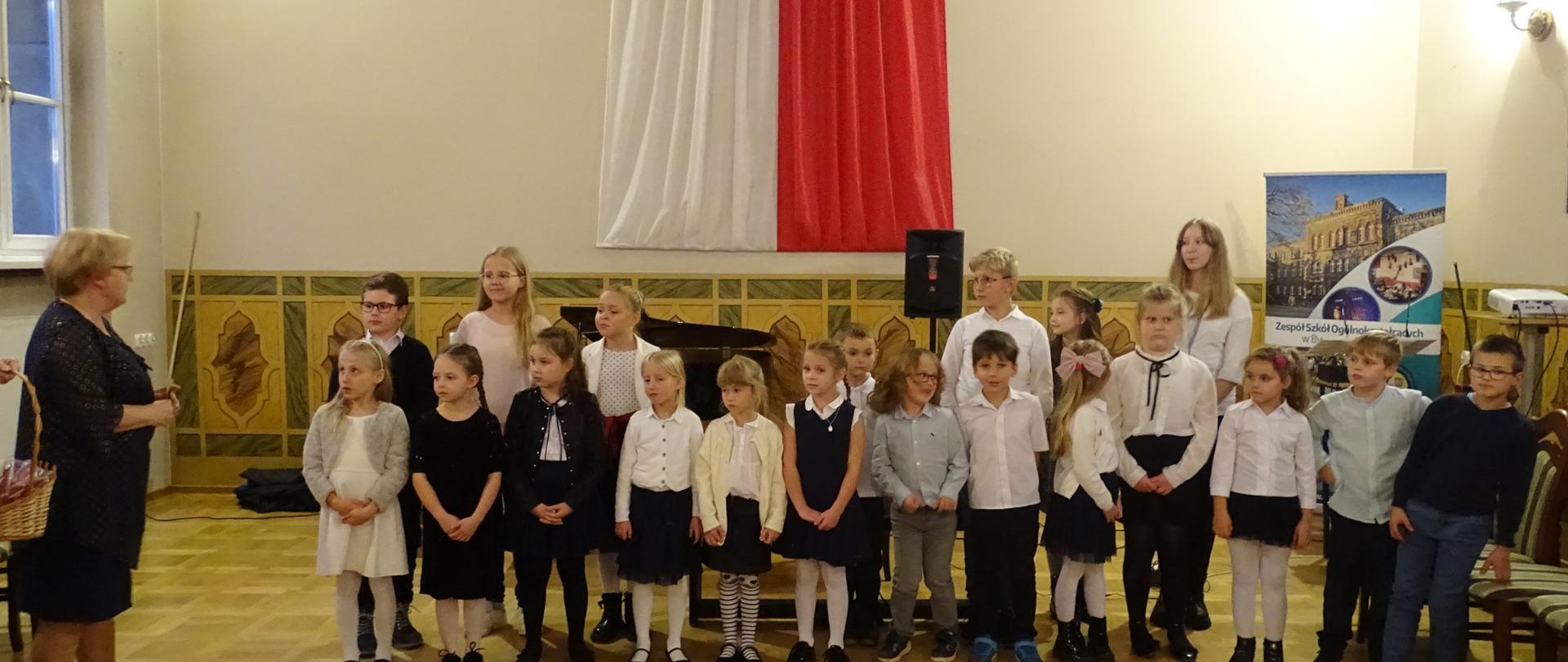 Zdjęcie przedstawia grupę uczniów podczas uroczystości pasowania klas pierwszych. 