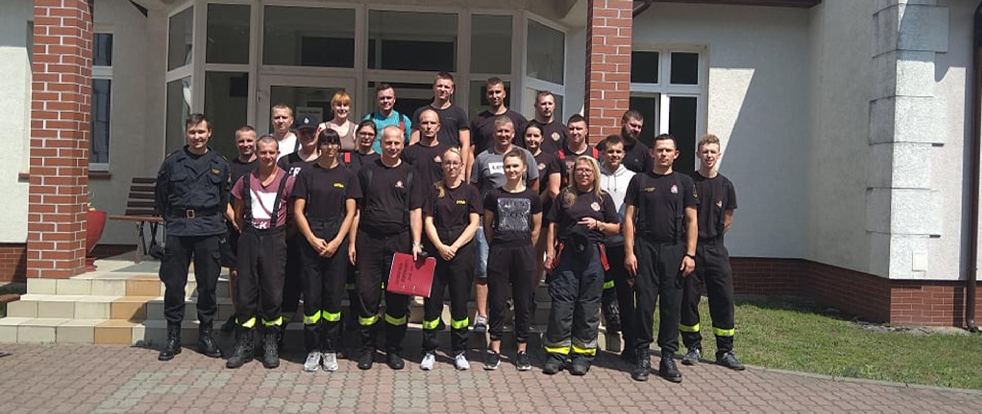Zdjęcie przedstawia uczestników szkolenia podstawowego strażaków ratowników Ochotniczych Straży Pożarnych na tle budynku Wojewódzkiego Ośrodka Szkolenia Państwowej Straży Pożarnej w Bornem Sulinowie