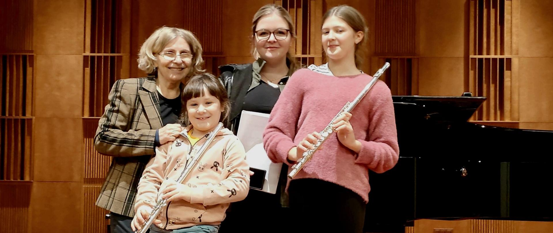 Zdjęcie przedstawia dzieci biorące udział w konkursie fletowym w Chełmie. Wraz z dziećmi pedagodzy. W tle fortepian.