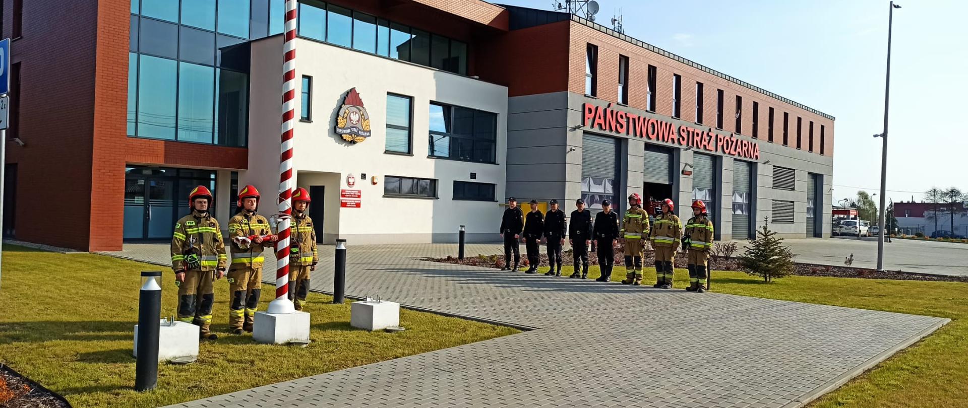 Na zdjęciu strażacy zmiany służbowej i funkcjonariusze komendy przed budynkiem komendy