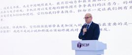 波兰驻广州总领事站在讲台前，在欧洲馆舞台上向观众发表讲话。总领事身后是一块大型屏幕，屏幕上显示着演示文稿。