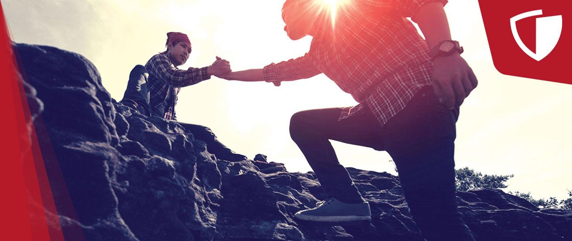 Grafika ze zdjęciem dwóch mężczyzn, jeden pomaga drugiemu wspiąć się na skały. W prawym górnym roku logo Tarczy Antykryzysowej.