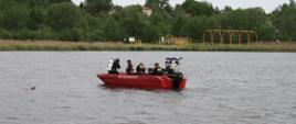 Strażacy z Świętokrzyskiej Grupy Ratownictwa Wodno-Nurkowego znajdują się w łodzi na zbiorniku wodnym i przygotowują Nurka do akcji ratowniczej.