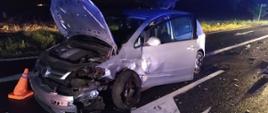 Zderzenie dwóch aut. Droga wojewódzka nr 309 w okolicach Żylic. Na jezdni stoi rozbity volkswagen golf. Pojazd ma mocno uszkodzoną swoją przednią lewą stronę. Auto jest koloru jasnego. Ma uniesioną pokrywę silnika. Przed samochodem stoi pachołek ostrzegawczy.