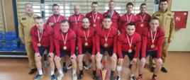 Zdjęcie grupowe wszystkich zawodników komendy państwowej straży pożarnej w brzezinach, komendanta oraz dowódcy jrg brzeziny, zdjęcie na hali na tle bramki wraz z pucharem za drugie miejsce