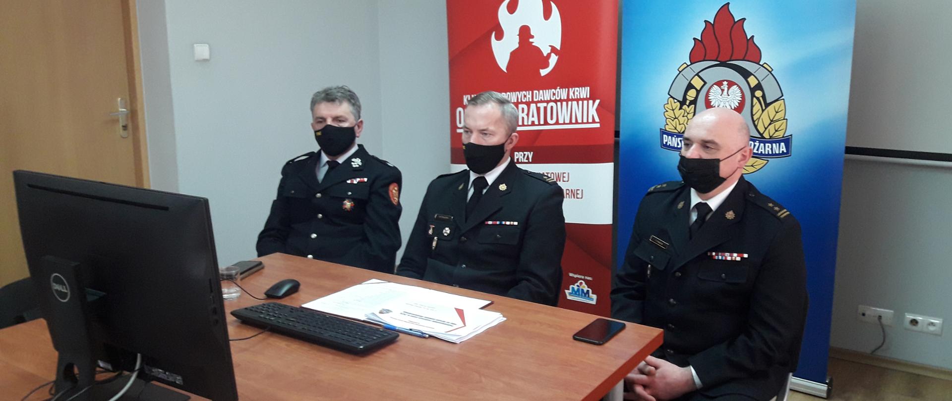 Na tle banneru KP PSP Limanowa Komendant Powiatowy PSP w Limanowej mł. bryg. W. Frączek, Zastępca Komendanta Powiatowego PSP w Limanowej bryg. T. Pawlik i prezes Zarządu Oddziału Powiatowego ZOSP RP w Limanowej st. bryg. w st. spocz. dh Grzegorz Janczy.