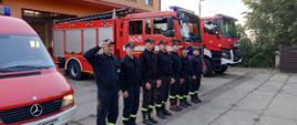 Strażacy przed wozem strażackim.