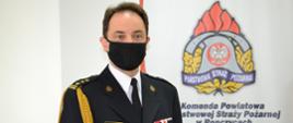 st. bryg. Janusz Piczak Z-ca Komendanta Powiatowego w mundurze galowym na tle logo PSP