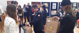 Na fotografii składając gratulacje zwycięzcom zastępca podkarpackiego komendanta wojewódzkiego PSP - st. bryg. Andrzej Marczenia. Strażak ubrany jest w mundur galowy koloru granatowego. W tle widać prace plastyczne uczestników konkursu.