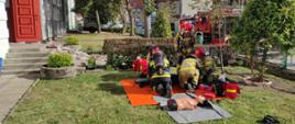 Zdjęcie przedstawia strażaków w trakcie ćwiczeń w Szkole Podstawowej nr 3 w Szczytnie, udzielanie kwalifikowanej pierwszej pomocy