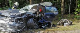 Zdjęcie przedstawia rozbity samochód marki VW Golf znajdujący się na poboczu drogi. 