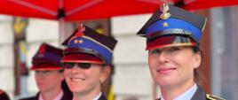 Funkcjonariuszki PSP w galowych mundurach i czapkach z niebieskim otokiem, uśmiechnięte i gotowe do udziału w dalszych uroczystościach. Kobiety PSP stanowią ważną część formacji ratowniczej.