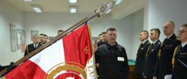 Strażak PSP składa ślubowanie na sztandar, strażacy w tle