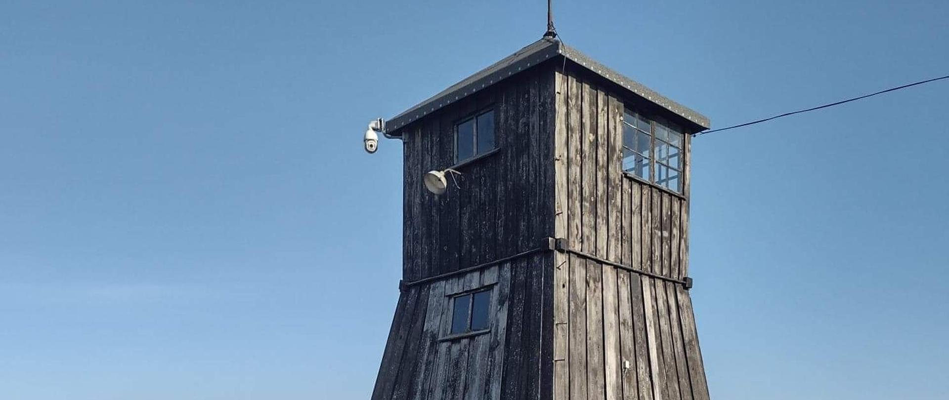 zdjęcie drewnianej wieżyczki strażniczej na tle niebieskiego nieba, muzeum Majdanek