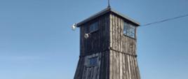 zdjęcie drewnianej wieżyczki strażniczej na tle niebieskiego nieba, muzeum Majdanek