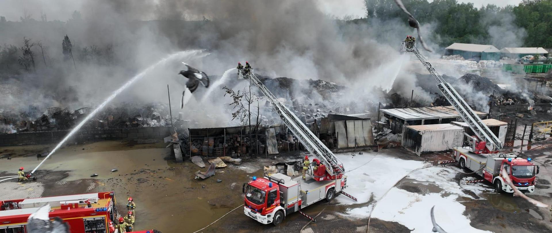 Na zdjęciu widać dogaszanie pożaru nielegalnego składowiska odpadów. Dwa prądy wody podawane z kosza drabiny mechanicznych i jeden prąd wody z działka przenośnego.