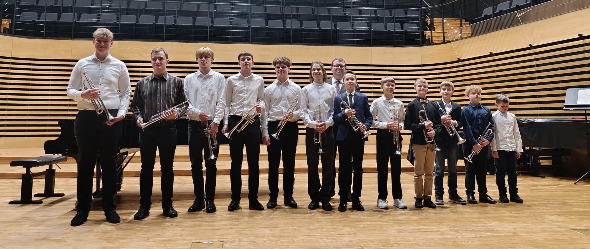 Wszyscy wykonawcy stoją na scenie.