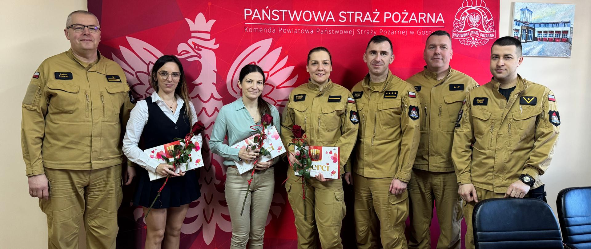 Funkcjonariusze stoją wraz z kobietami w sali konferencyjnej.