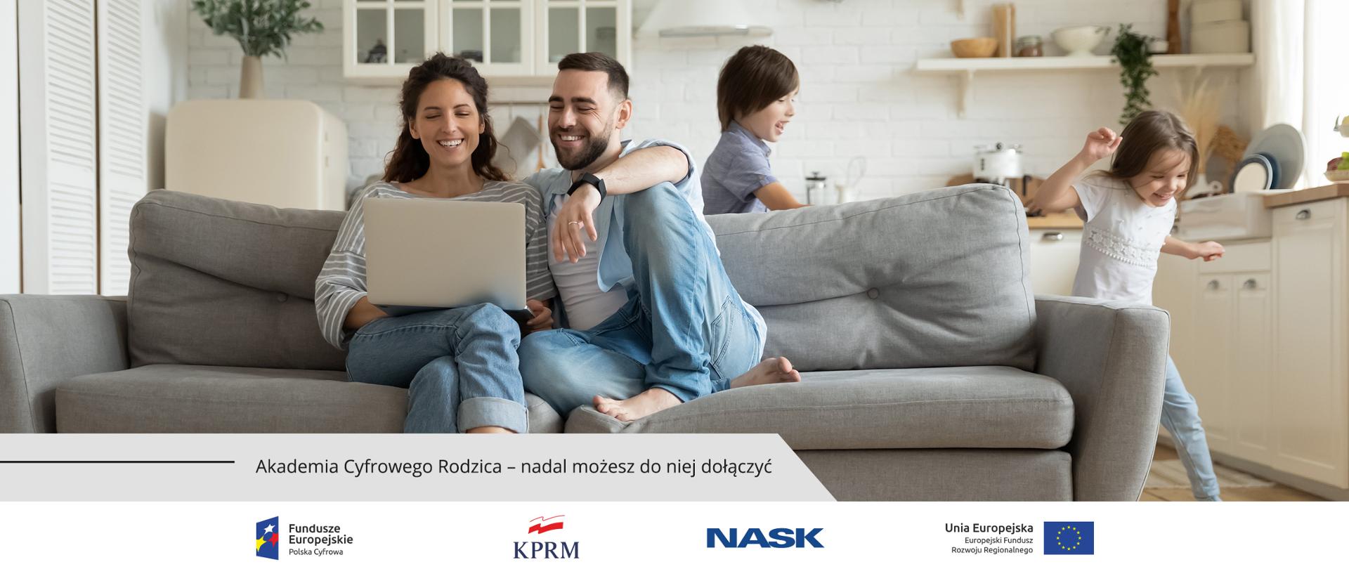 Uśmiechnięci rodzice siedzą na kanapie, oglądają coś na laptopie. Za nimi, wokół kanapy, biegają dzieci (chłopiec i dziewczyna).