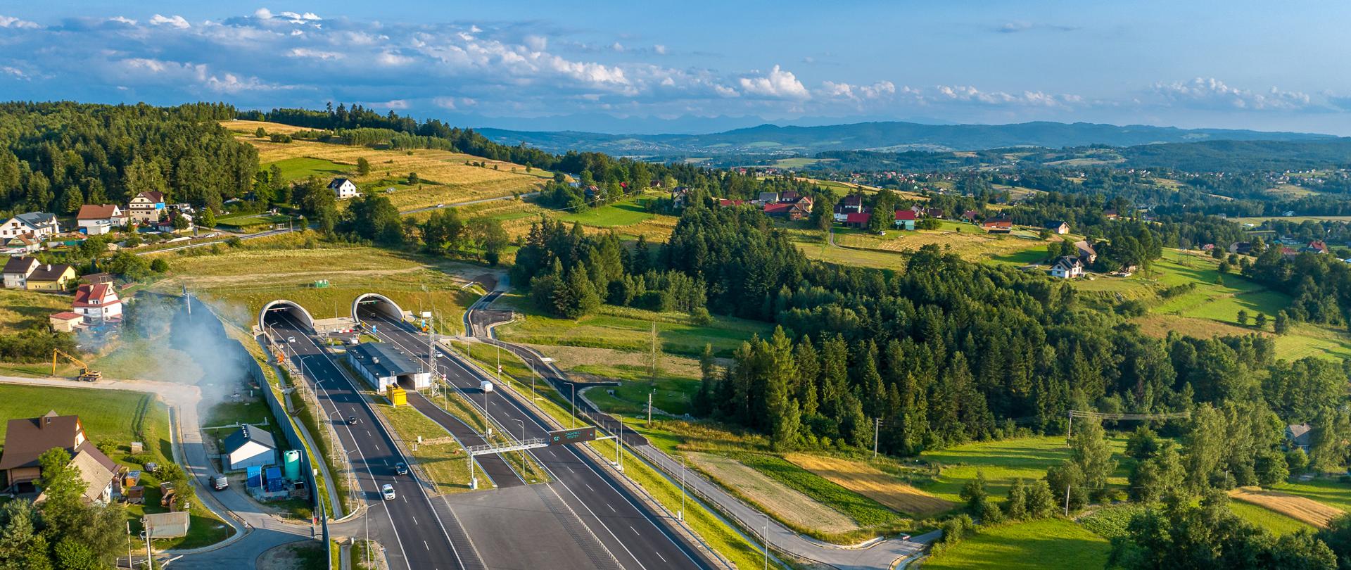 Wjazd do tunelu przebiegającego przez górę, dookoła dużo zieleni