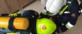 Na zdjęciu widoczni strażacy w ubraniach specjalnych koloru granatowego w hełmach strażackich oraz udzielający kwalifikowanej pierwszej pomocy poszkodowanemu podczas ćwiczeń na oddziale geriatrycznym w szpitalu specjalistycznym w Gorlicach.
