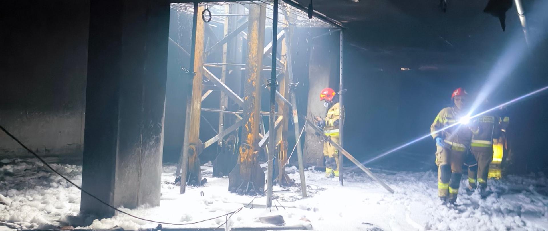 Czterech strażaków, w umundurowaniu specjalnym, w trakcie działań gaśniczych