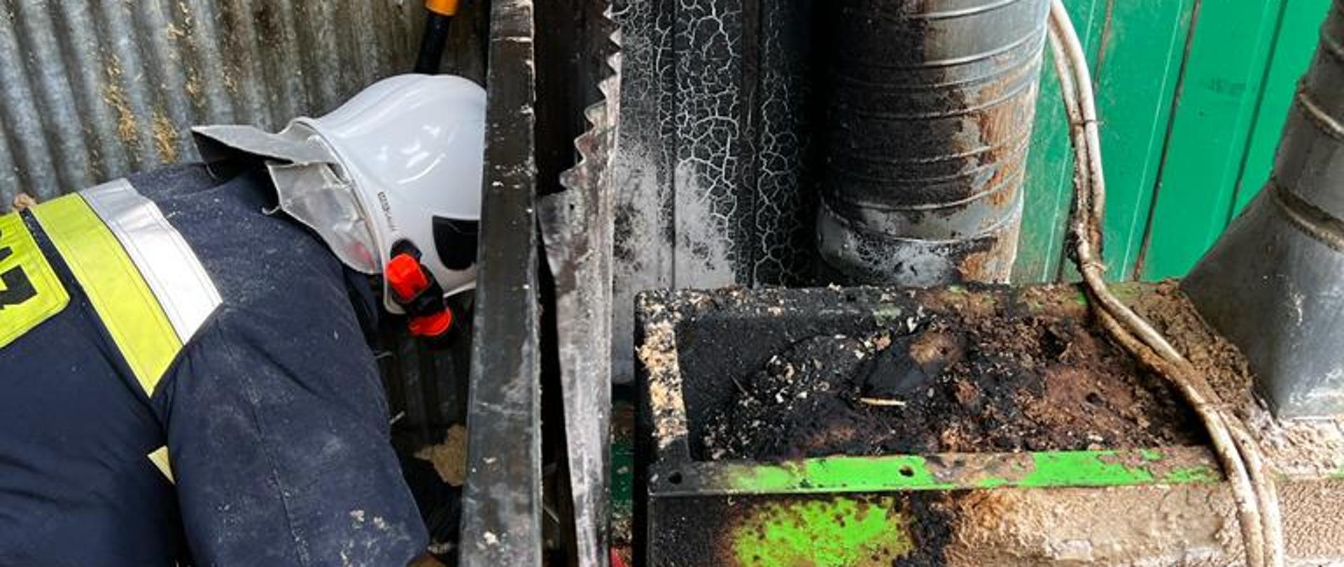 Strażak prowadzi prace rozbiórkowe w stolarni.