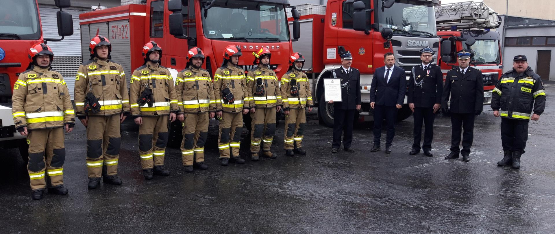 Ustawieni w rzędzie strażacy w mundurach bojowych obok nich Komendant Powiatowy z Zastępcą oraz przedstawicielam Gminy Prusice, Komendantem Gminnym OSP Prusice oraz Prezesem OSP Pawłów Trzebnicki