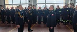 Zdjęcie przedstawia zdającego i przejmującego pełnienie obowiązków Komendanta Powiatowego PSP w Pruszczu Gdańskim podczas składania meldunku pełniącemu obowiązki Komendanta Wojewódzkiego