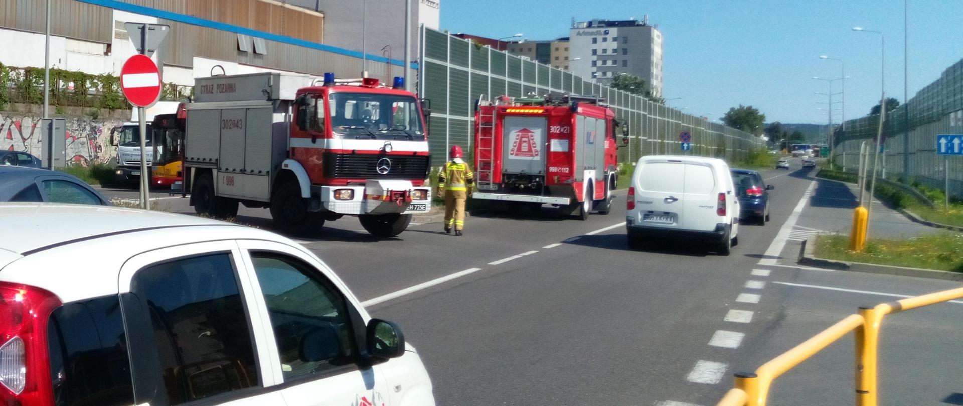 Widok na ulicę Zagnańską w Kielcach. W centralnym punkcie zdjęcia dwa samochody pożarnicze zabezpieczające miejsce zdarzenia stojące wśród poruszających się aut.