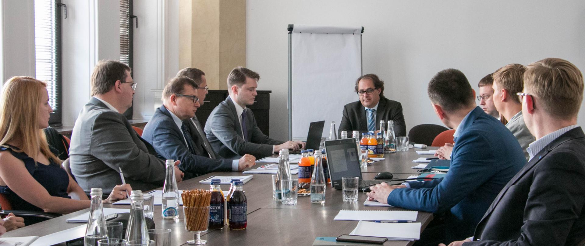 Przy stole siedzą uczestnicy spotkania, przemawia minister Marek Gróbarczyk.