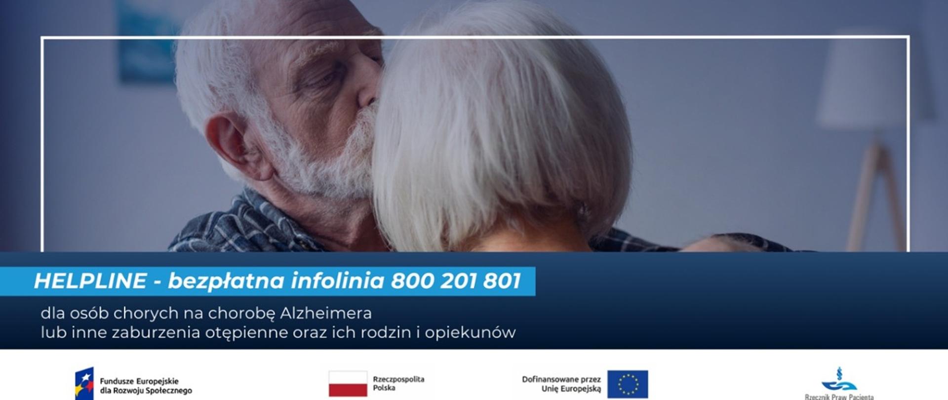Starszy, siwy mężczyzna obejmujący ramionami starszą, siwą kobietę. W tle na niebieskim pasku umiejscowiony jest napis HELPLINE – bezpłatna infolinia 800 201 801 dla osób chorych na chorobę Alzheimera lub inne zaburzenia otępienne oraz ich rodzin i opiekunów.