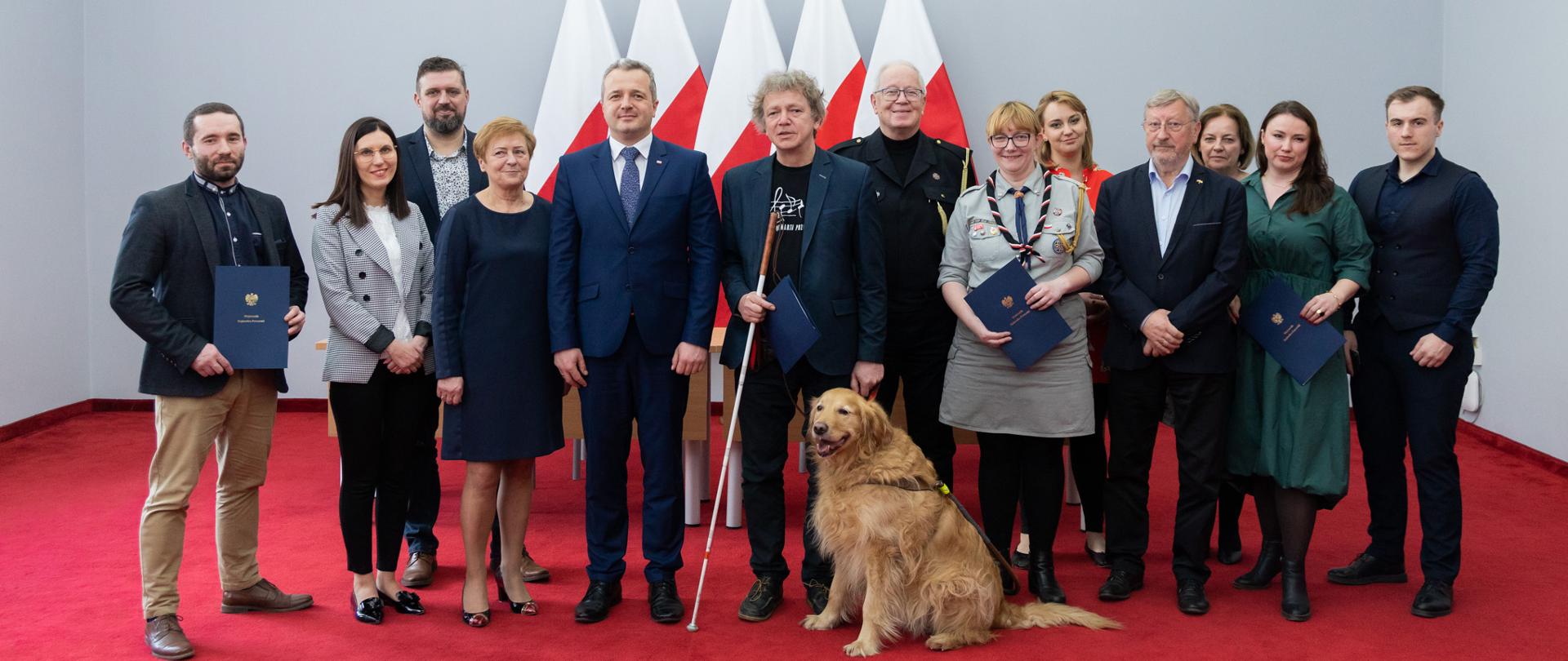 Wiele osób i pies pozujących do zdjęcia