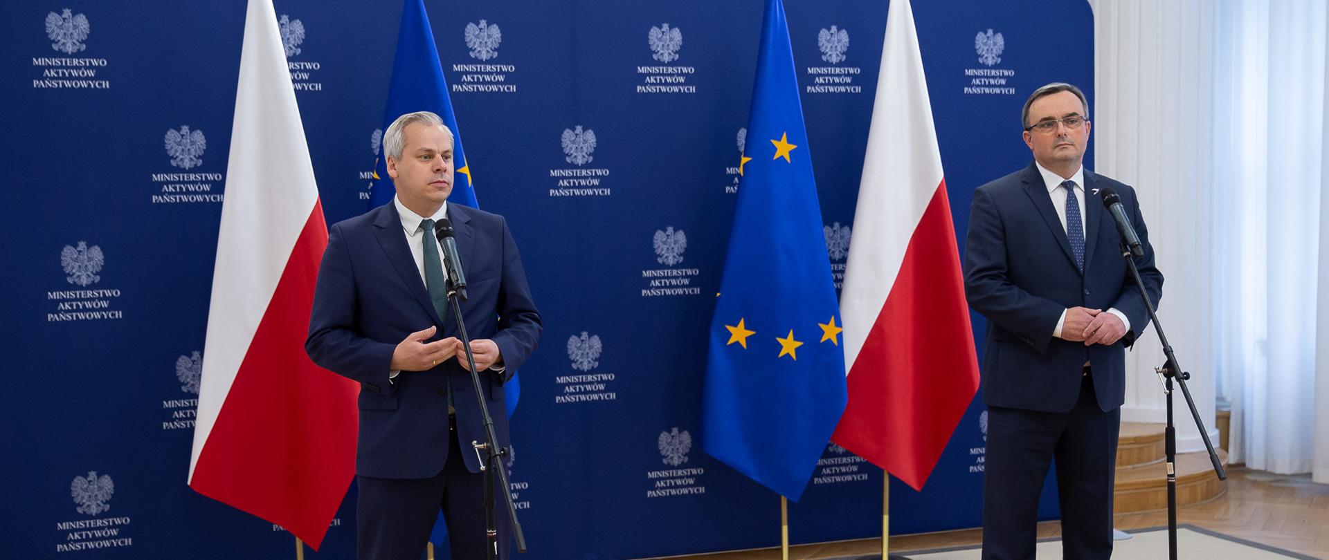 Wiceminister Karol Rabenda i Prezes Grupy Azoty S.A. Tomasz Hinc stoją przy mikrofonach, bliski plan. W tle ścianka z logotypami MAP oraz flagi - polska i unijna. 