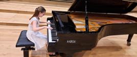 Uczennica grająca na fortepianie na scenie sali koncertowej PSM