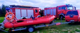 Wozy strażackie wraz z łodzią na zielonej trawie 