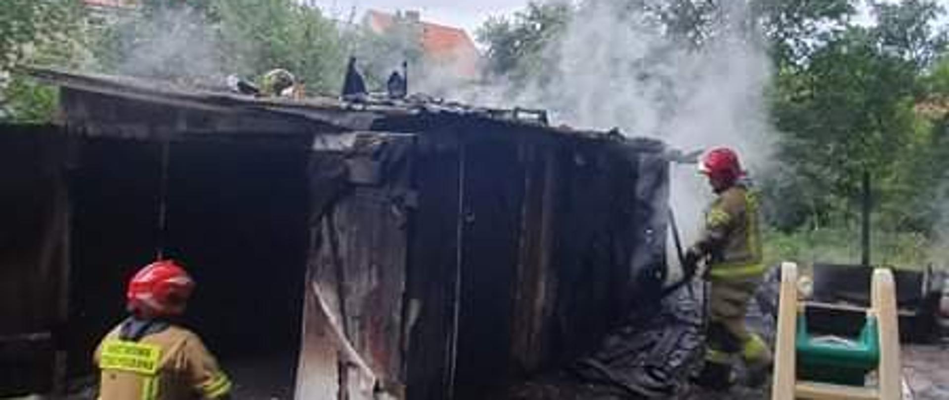 
Fotografia przedstawia działania strażaków podczas pożaru garażu.