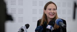 
In the photo, Minister Katarzyna Pełczyńska-Nałęcz during a press conference, standing in front of the microphones