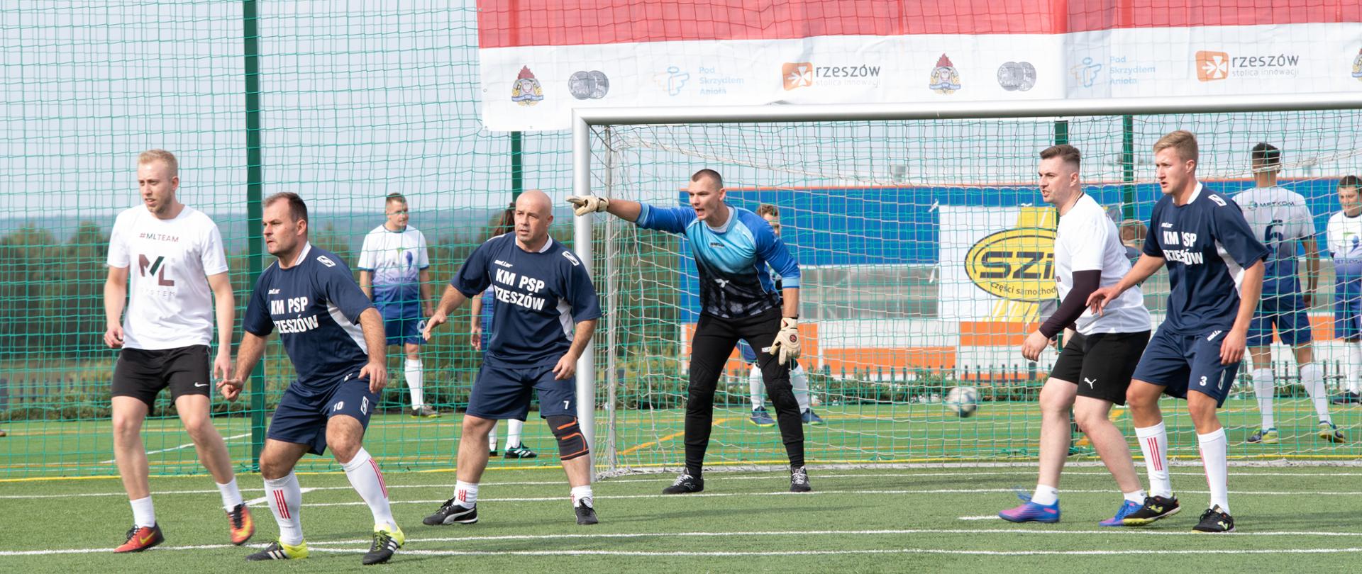Zdjęcie przedstawia piłkarzy podczas meczu Komendy Miejskiej Państwowej Straży Pożarnej w Rzeszowie z piłkarzami firmy ML System +. 