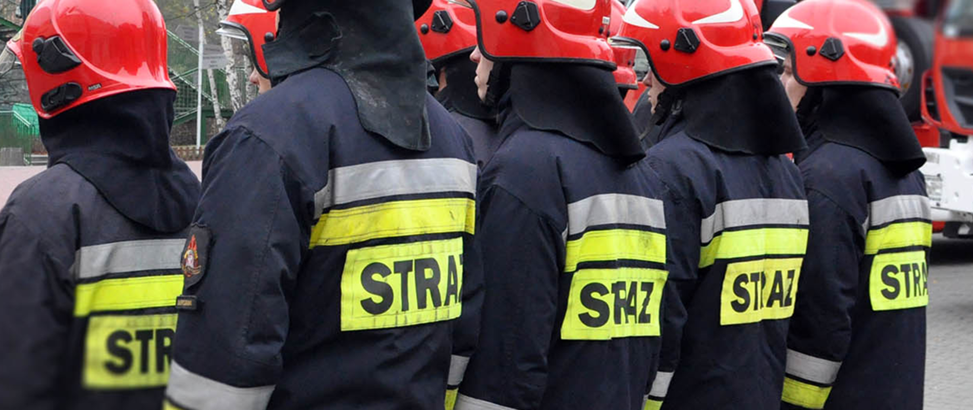 Na zdjęciu widać strażaków stojących w dwóch rzędach w umundurowaniu specjalnym z napisem "STRAŻ" na plecach.