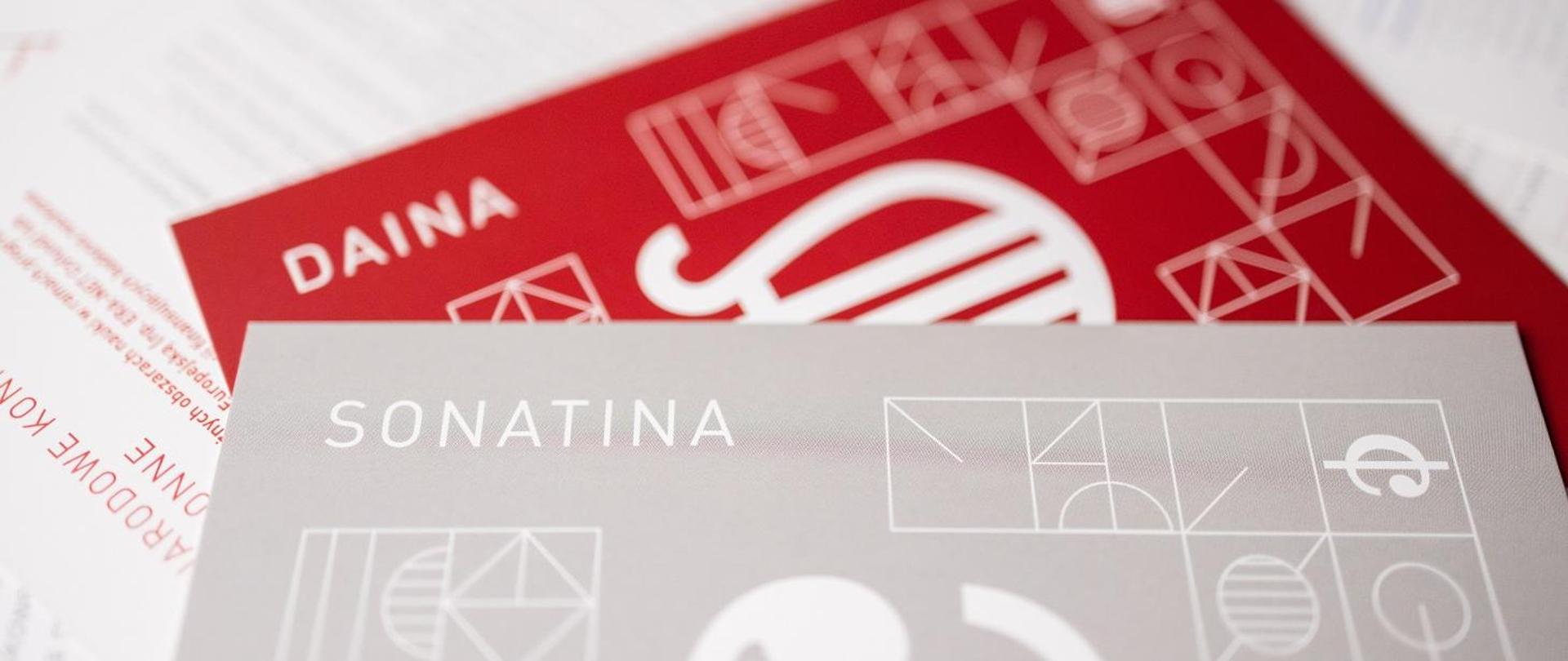 Grafika - szara i czerwona kartka z symbolami naukowymi i napisami Sonatina i Daina.