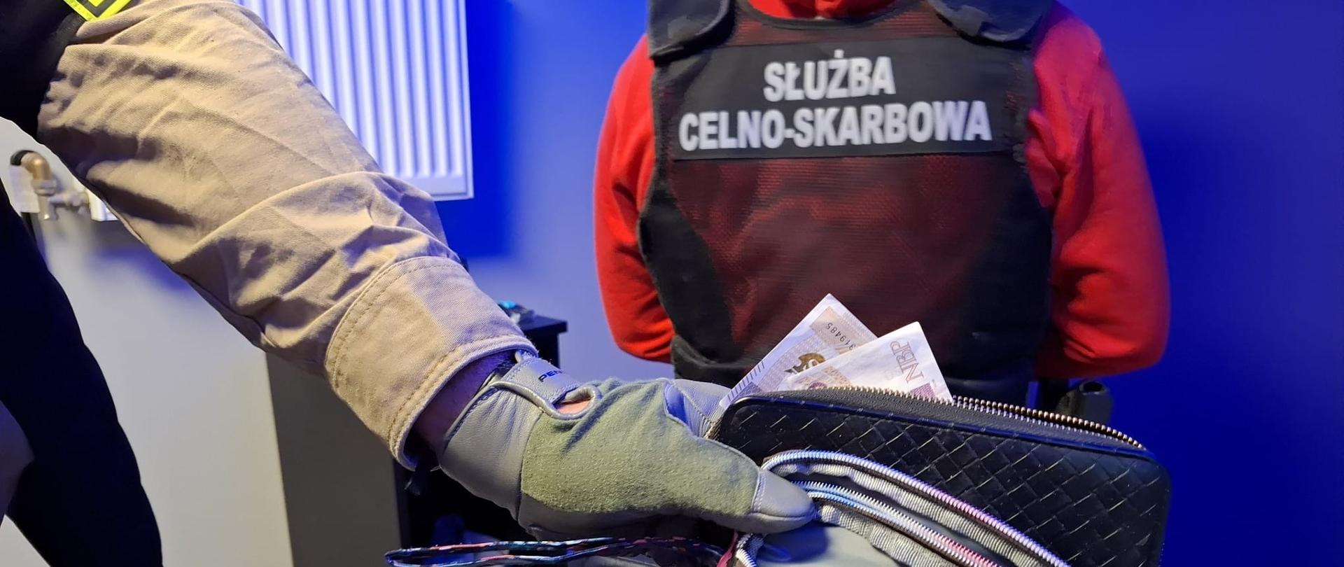 Funkcjonariusz pokazujący zabezpieczoną gotówkę w portfelu