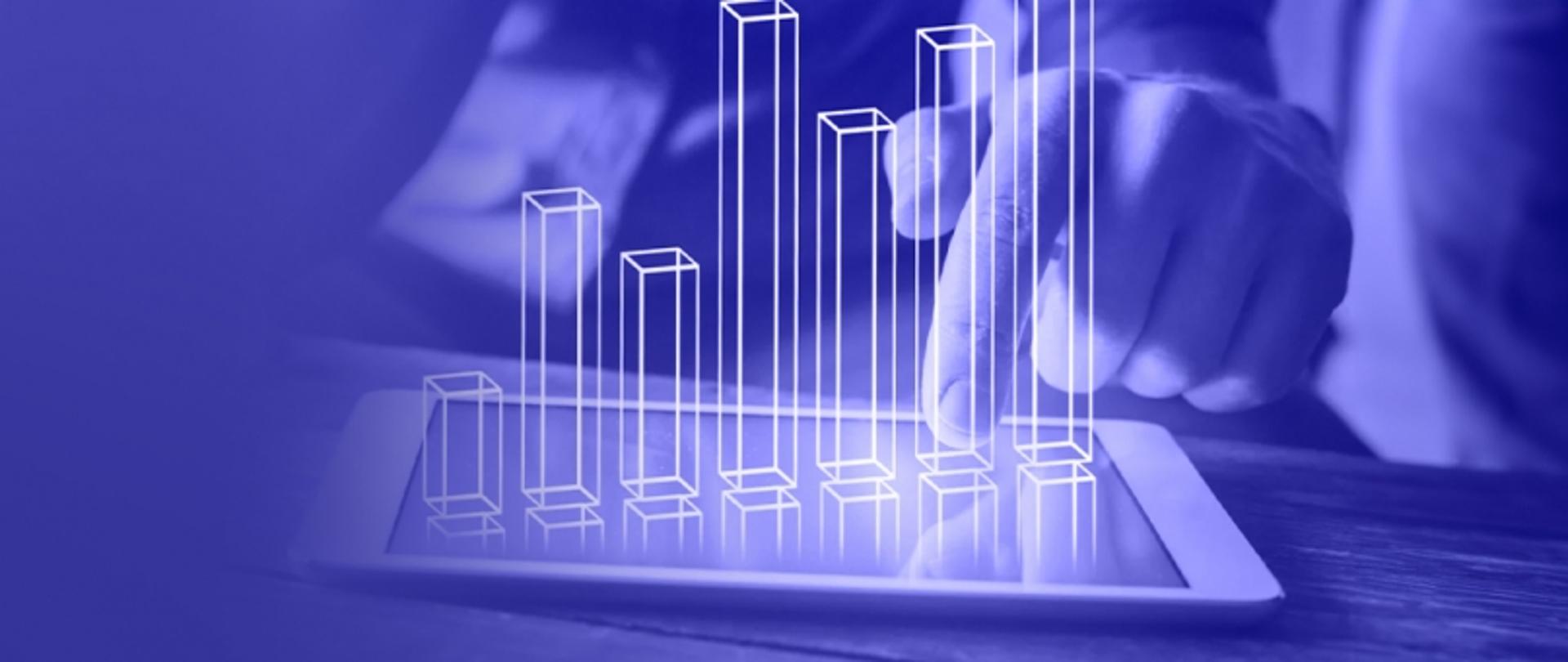 Zdjęcie przedstawia osobę dotykającą ekran tabletu z wyświetlonymi wirtualnymi wykresami słupkowymi w tonacji niebieskiej.